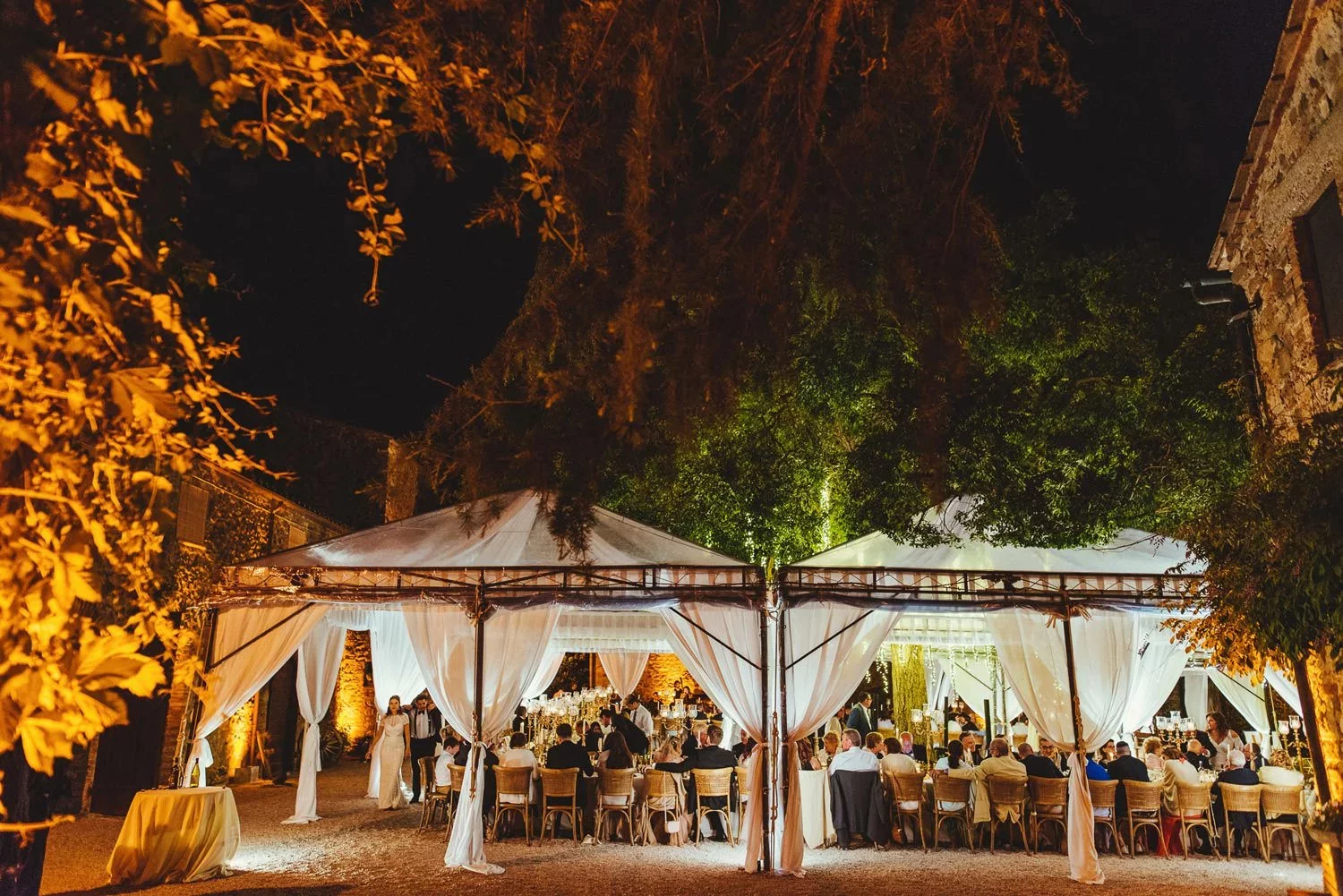 An outdoor wedding reception under decorated gazebos at Borgo Di Castelvecchio in Tuscany, Italy.