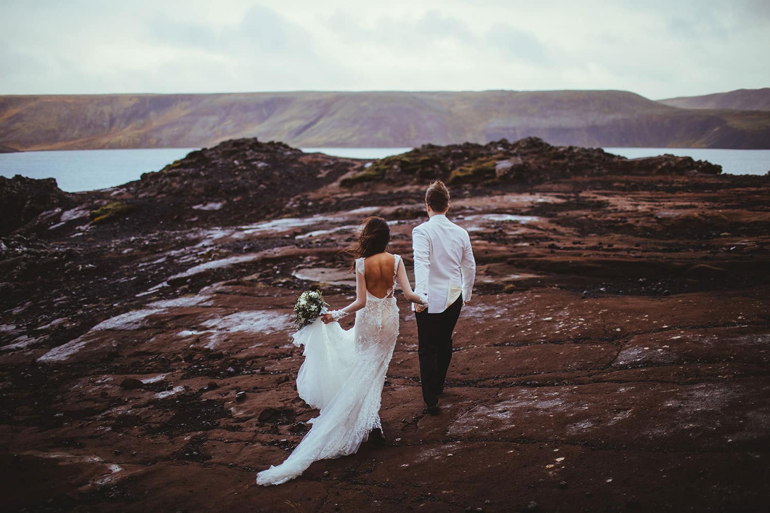Iceland is a fantastic place to Elope in Europe as this pic of a bride and groom strolling over a lava field shows.