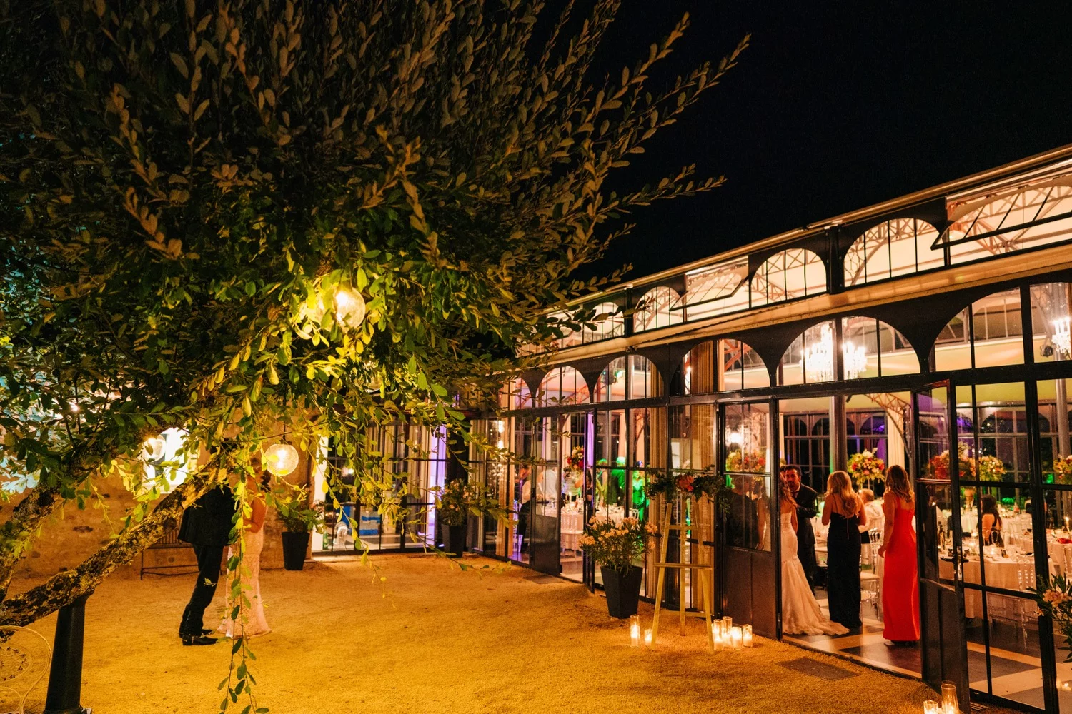 Guests celebrate in the Orangerie at Domaine La Fauconnie in France at night at a wedding reception.